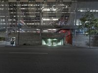 a empty parking garage under an indoor bridge on a city street at night time, in the middle of a wide street