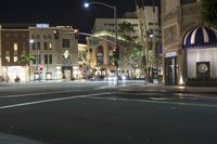 the street is empty as cars drive down it at night, including the traffic light