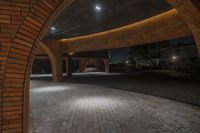 an arched wall is set around a cobblestone patio in the dark night hours