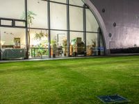 a large open grassy lawn next to glass doors in the evening time of the day