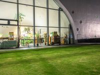 a large open grassy lawn next to glass doors in the evening time of the day