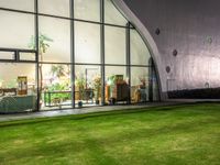 a large open grassy lawn next to glass doors in the evening time of the day