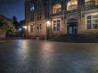 the front entrance of a school building at night with a bench on the steps and lighted stairs in front of it