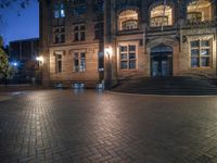 the front entrance of a school building at night with a bench on the steps and lighted stairs in front of it