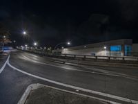 a very big long street by some building at night with lights on it's sides