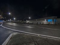 a very big long street by some building at night with lights on it's sides