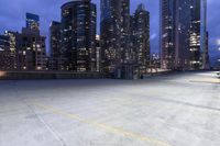 a large parking lot in a city next to tall buildings at night in the dark