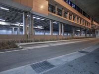 the empty street is in front of the building by itself at night under the sidewalk