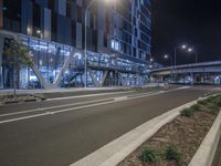 an empty road next to a city street at night with a walkway in front and a car coming up out the side