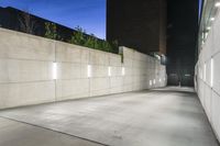 the large concrete wall has been illuminated by recessed lights at night on either side of it