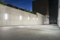 the large concrete wall has been illuminated by recessed lights at night on either side of it