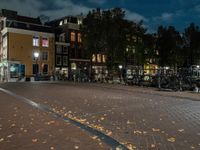 bicycles are parked along the edge of a walkway on a night time sidewalk near a building