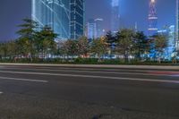 a city street with buildings and neon lights at night time in hong china as seen from an empty city highway