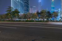 a city street with buildings and neon lights at night time in hong china as seen from an empty city highway