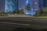 a city street with buildings and neon lights at night time in hong china as seen from an empty city highway