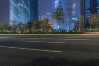 a city street with buildings and neon lights at night time in hong china as seen from an empty city highway