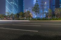 a city street with buildings and neon lights at night time in hong china as seen from an empty city highway