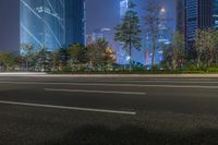 a city street with buildings and neon lights at night time in hong china as seen from an empty city highway