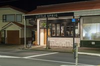 a street at night with a cafe in the corner and a bus coming out of it