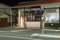 a street at night with a cafe in the corner and a bus coming out of it