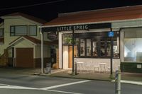 a street at night with a cafe in the corner and a bus coming out of it