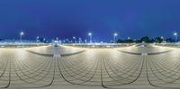 a very wide angle view of a walkway that has benches and lights in it,