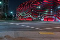 an american flag building with red and silver lights at night in a city street or street corner