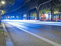 cars driving down a city street next to tall buildings at night, and a bridge