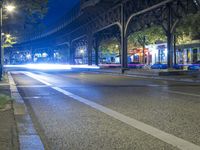 cars driving down a city street next to tall buildings at night, and a bridge