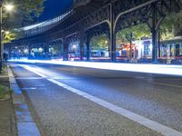 cars driving down a city street next to tall buildings at night, and a bridge