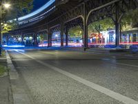 cars driving down a city street next to tall buildings at night, and a bridge