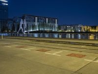 the woman with a suitcase is walking along the river near a building at night in a city