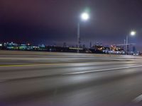 a blurry image of the highway in night time with lights reflecting off of the asphalt