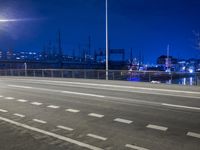 a road with a bridge across it near a large building at night time with traffic