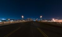 a road and some lights over a bridge in front of the sky at night,