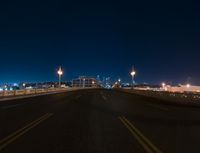 a road and some lights over a bridge in front of the sky at night,