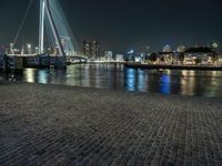 a bridge over a body of water with many lights on it at night time and other buildings next to the water