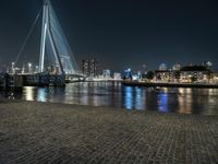 a bridge over a body of water with many lights on it at night time and other buildings next to the water