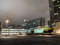 a parking lot in a city with cars on the road at night time and buildings