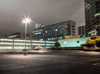 a parking lot in a city with cars on the road at night time and buildings