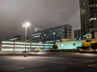 a parking lot in a city with cars on the road at night time and buildings