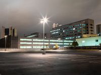 a parking lot in a city with cars on the road at night time and buildings