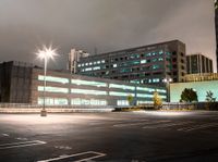 a parking lot in a city with cars on the road at night time and buildings