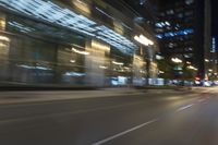 cars driving in the city in motion on a highway at night time, with buildings and traffic