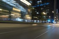 cars driving in the city in motion on a highway at night time, with buildings and traffic