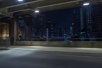 cars travelling down an empty highway with the city skyline visible in the background, along with an overpass