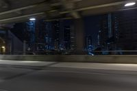 cars travelling down an empty highway with the city skyline visible in the background, along with an overpass