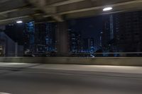 cars travelling down an empty highway with the city skyline visible in the background, along with an overpass