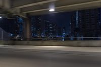 cars travelling down an empty highway with the city skyline visible in the background, along with an overpass