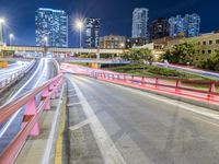 an expressway highway has blurred traffic on it at night time and there are many buildings in the background